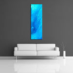 A modern abstract painting featuring the colours  light and dark blue. Displayed vertically above a couch.