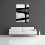 An abstract painting featuring strong black lines over solid white and gray paint. This painting is displayed on a wall