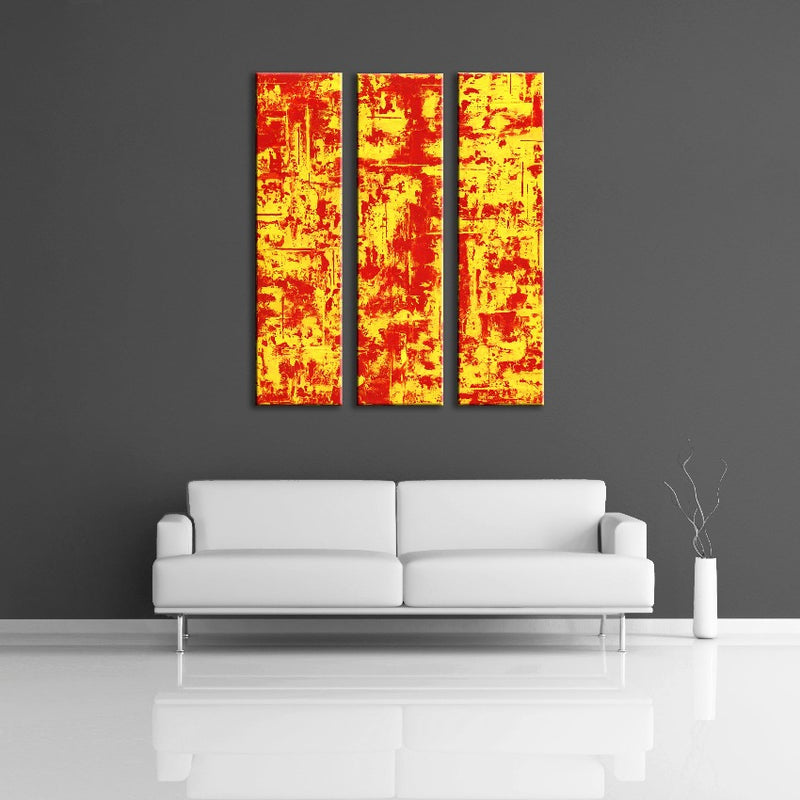 A multi-paneled, modern abstract painting featuring the colours red and yellow. Displayed on a wall.