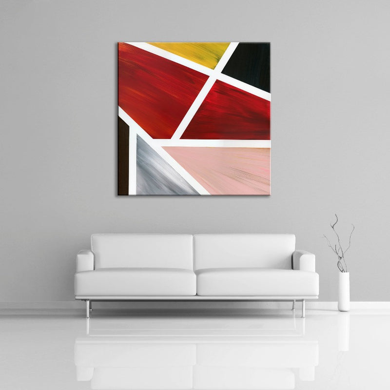 A geometric abstract painting featuring the colours black, red, yellow pink and brown. Displayed over a couch.