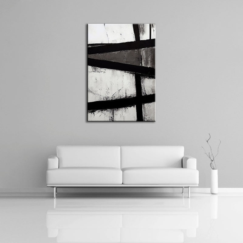 An abstract painting featuring strong black lines over solid white and gray paint. This painting is displayed over a white couch