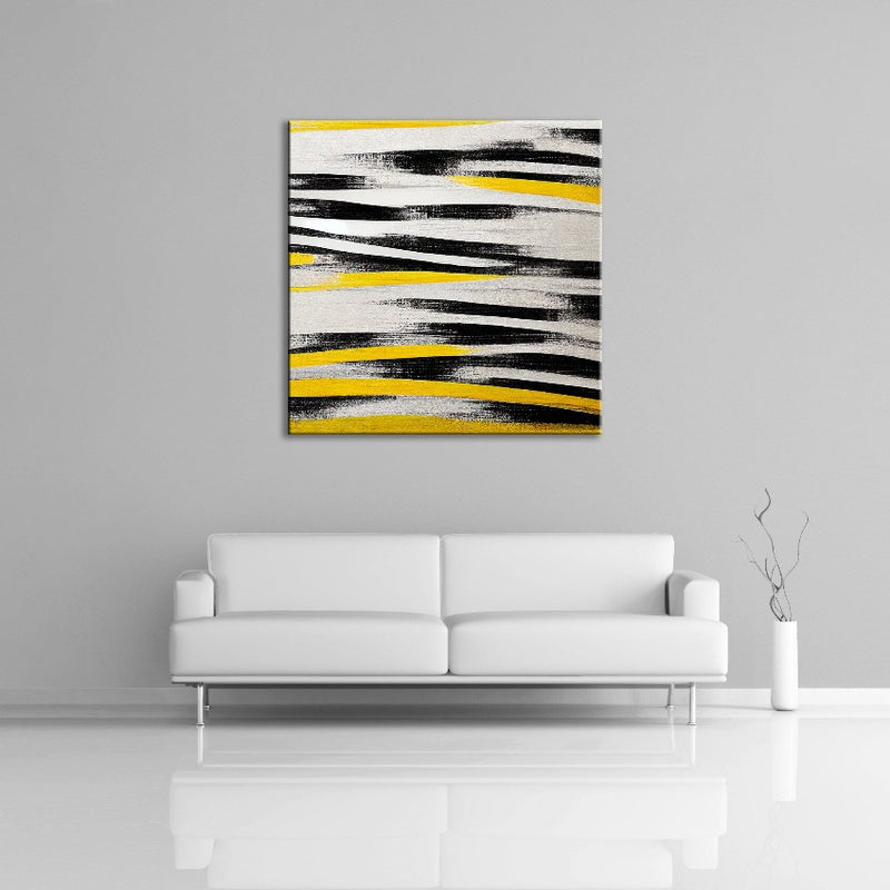 An abstract painting featuring yellow, black and white.  Displayed over a couch